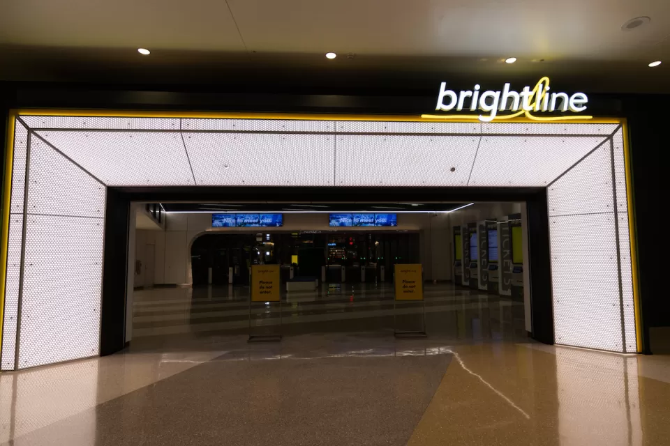 Empty, darkened corridor in transit station before opening with Brightline logo in lights on one side